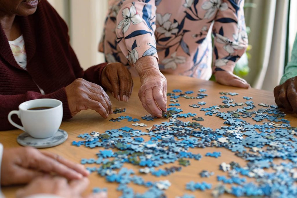 seniors put a puzzle together which is one of many activities for seniors with alzheimer's