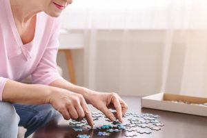 senior woman puts together a puzzle and one example of cognitive exercises for seniors