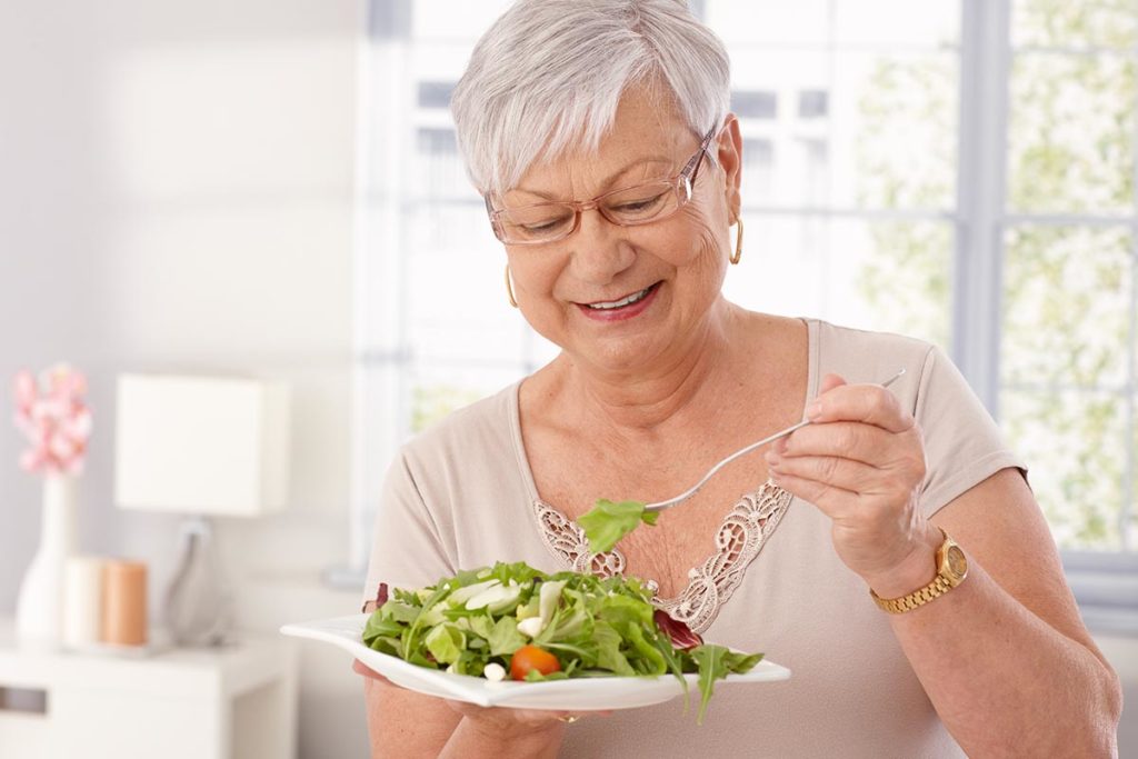 senior woman eating a salad and realizing the link between diet and dementia
