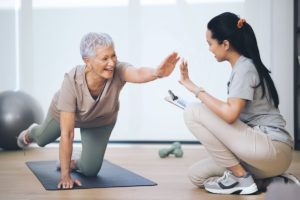 senior woman practices yoga with help from her physical therapist who recommends balance exercises for seniors