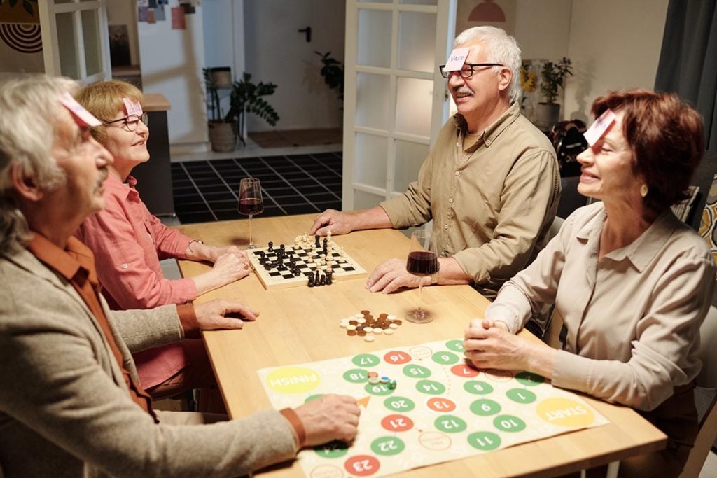 a group of seniors play board games which is one activity to do with a senior with limited mobility