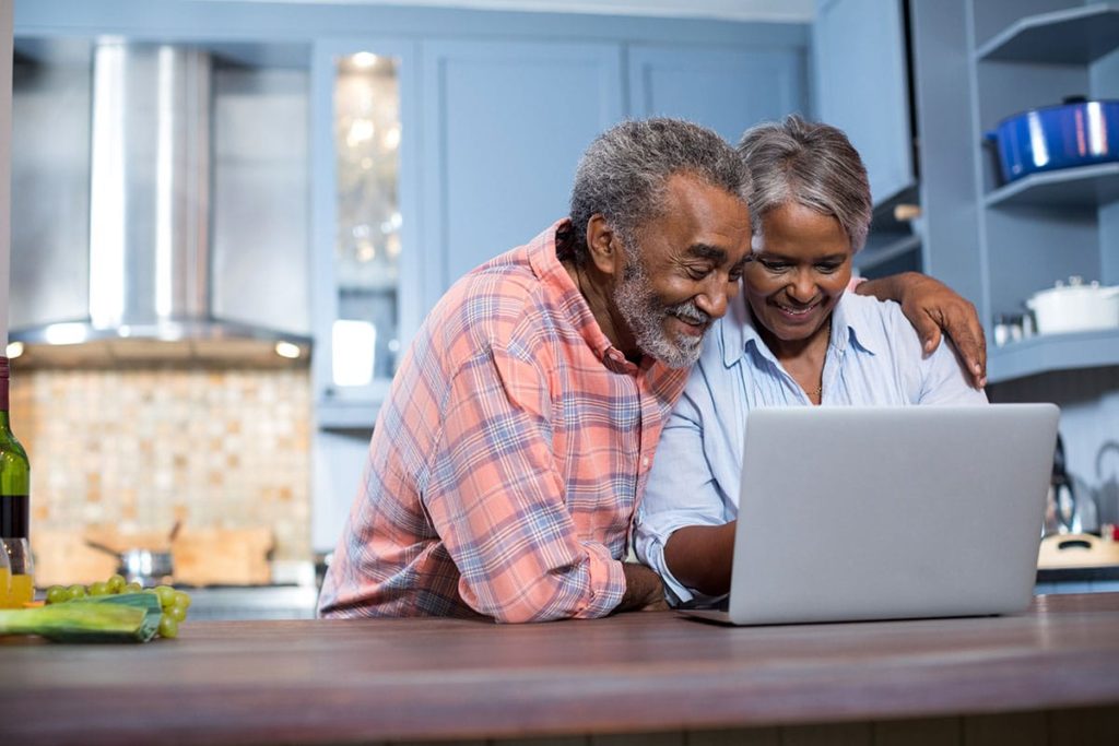 a senior couple sits in front of their laptop researching tips to find a retirement home