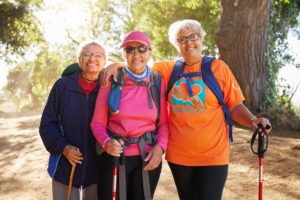 three older adult women in hiking gear on a hiking trail following some of the tips for seniors to stay active