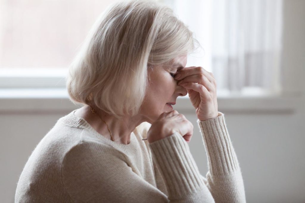 a senior woman sits exhausted and defeated and might be showing signs of anxiety in seniors