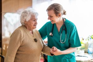 a nurse helps a senior woman with getting up and explaining to the senior woman about what is skilled nursing care