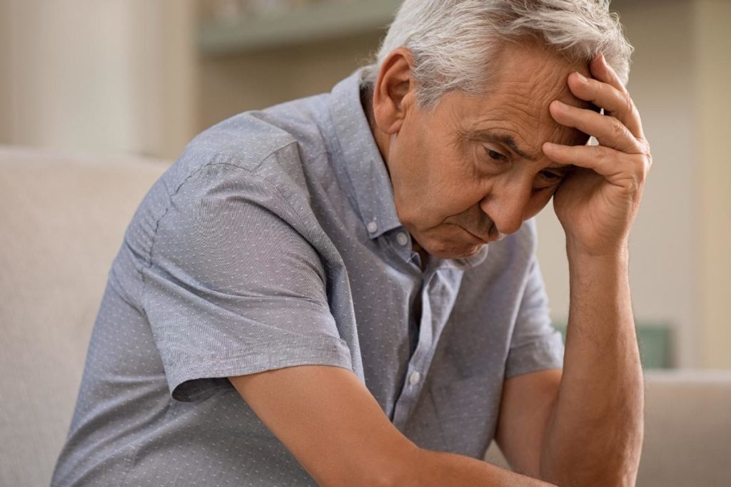 a senior holds their head looking sad, possibly struggling with signs of depression in seniors