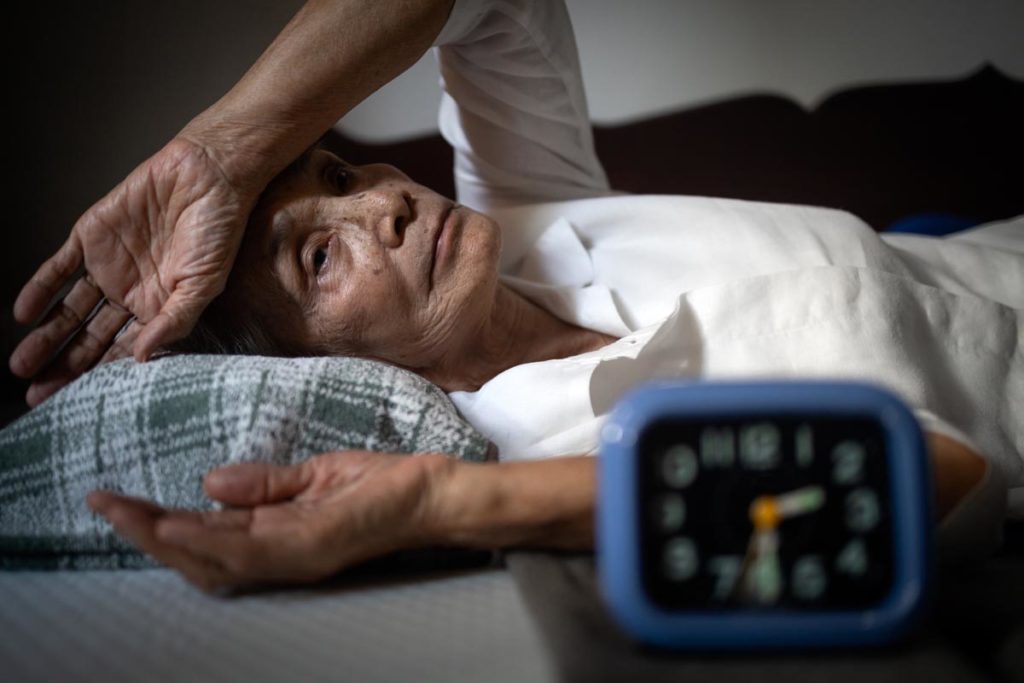 one of many seniors with anxiety lies in bed during the day