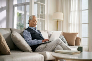 a senior uses a laptop on a couch to research independent senior living