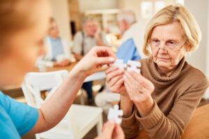 A senior adult woman with Alzheimer's is putting a puzzle together.