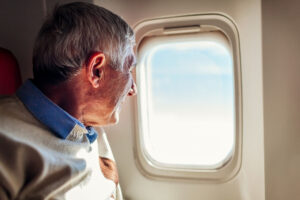 a senior travels in retirement and looks out a plane window