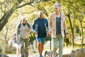 three senior adults walk outside after learning how to stay active in retirement