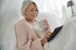 A senior adult woman reads senior living testimonials on her iPad.
