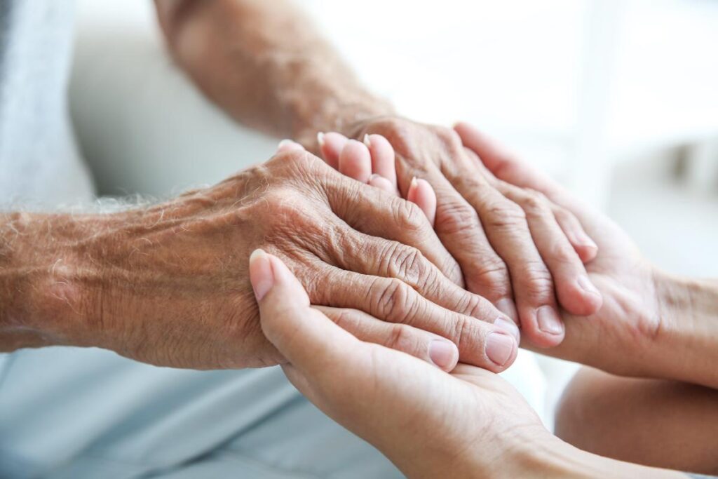 A senior adult receiving various therapies in short-term rehabilitation for seniors holds hands with a younger adult.