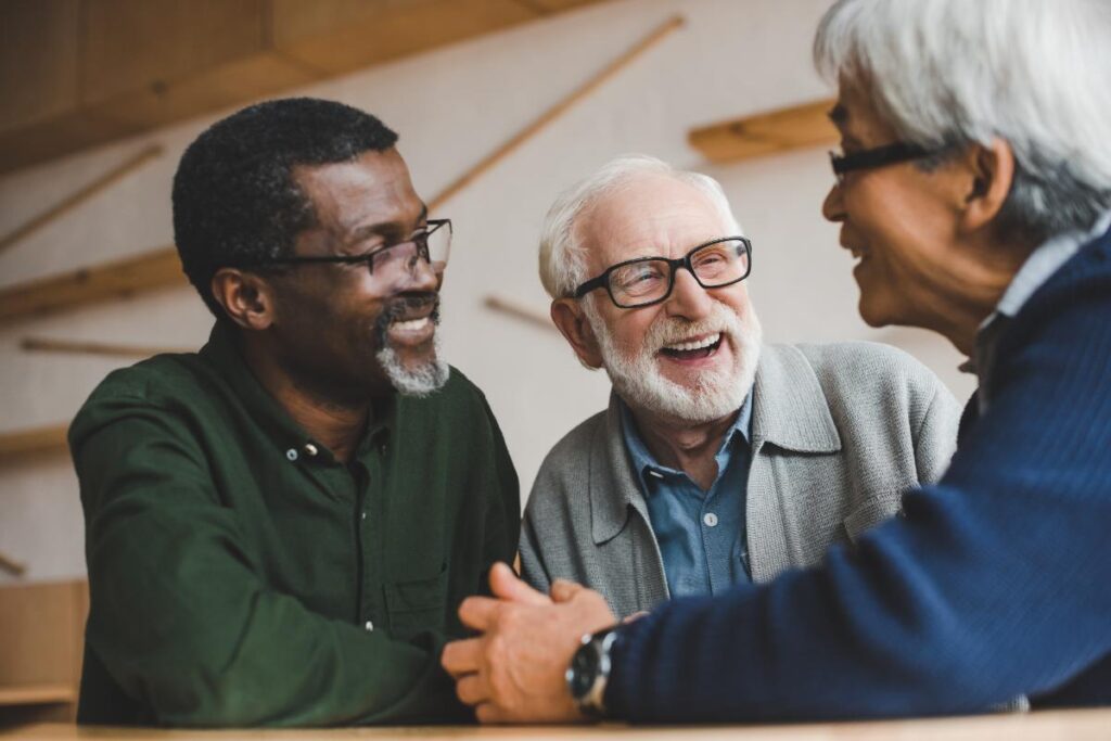 Three men of different races and ethnicities are enjoying each others company and benefiting from diversity and inclusion in senior living communities.