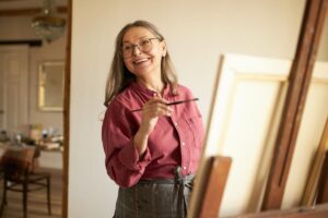 A woman enjoys painting as an engaging hobby and activity for seniors.