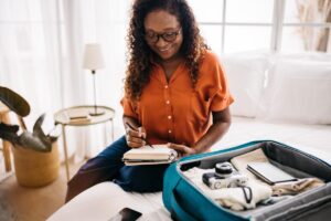 A senior woman benefits from traveling tips for seniors, by using a packing list as she places things into her suitcase.