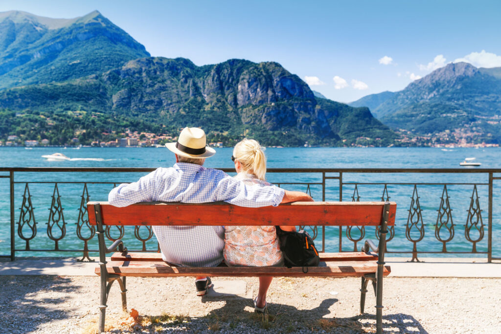 A couple sits on a bench overlooking an ocean view. They're enjoying one of the top senior-friendly travel destinations.